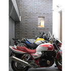 家の中心にバイクを置くレンガのデザイン住... バイクガレージ