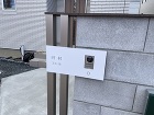 大阪府箕面市のシンプルなエクステリアに添えられたオリジナル表札です。樹脂パネルにお名前を入れた表札がそのままインターホンカバーになっているデザインです。