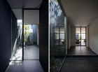 （左）ポーチより玄関を望む。玄関土間の先には坪庭を設けている。（右）玄関より奥のリビングを望む。リビングドアはスチール製ガラス戸としている。　 © photo Akiyoshi Fukuzawa