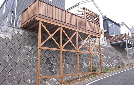 玄関わきのアプローチからのウッドデッキとパーゴラ