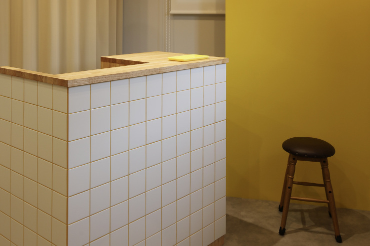 黄色をアクセントカラーにした美容室カウンター。タイル　黄色目地