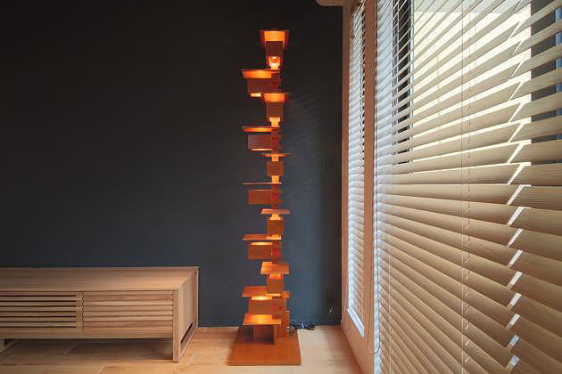 リビングの黒い壁と、フロアスタンドの明かりと、木製ルーバーの構成