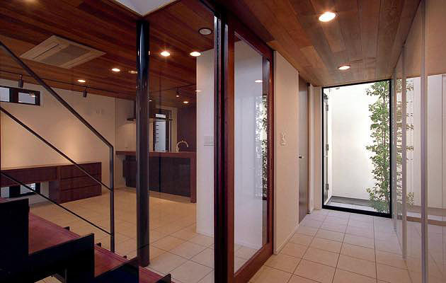 モダンデザインの住宅,ガラスで間仕切られた玄関ホールとリビングの繋がり,大型犬との生活のため1Ｆ床は全てタイル貼り