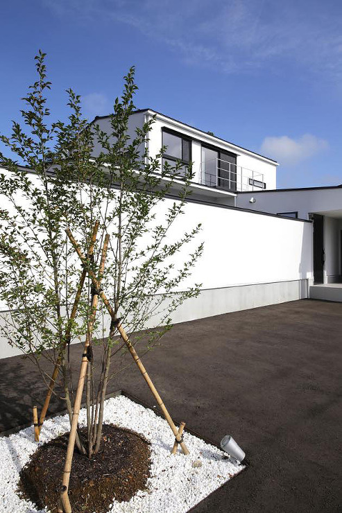 水平ラインを強調し、白い壁で囲まれた中庭を持つ、モダンデザインの住宅外観2