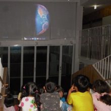 お泊り保育時、大階段に座ってプラネタリウム観賞する園児たち。<br />
（先生撮影）