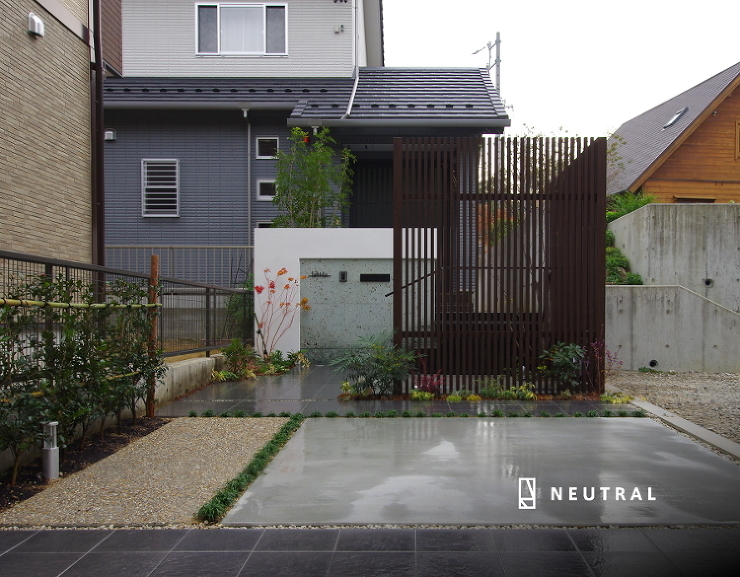 間口を広く見せるアプローチ、門構えのインパクトで旗竿地を生かしています。<br />
モノトーンの建物に華を添えるように、カラーリーフを豊富に配置した外構。