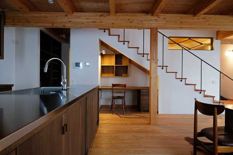 照明をつけた時の階段下ニッチのワークスペースとカラマツ集成材の2階床梁の渡りアゴ掛け組みと大黒柱