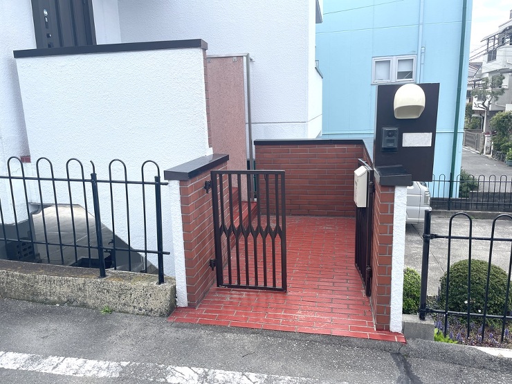 門まわりのリフォーム前の様子です。インターホンの付いた黒い部分をとると手すりにも影響するのでそのまま表面材だけ工夫することで手間とコストを省きます。古いポンぴとポストも変更していきます