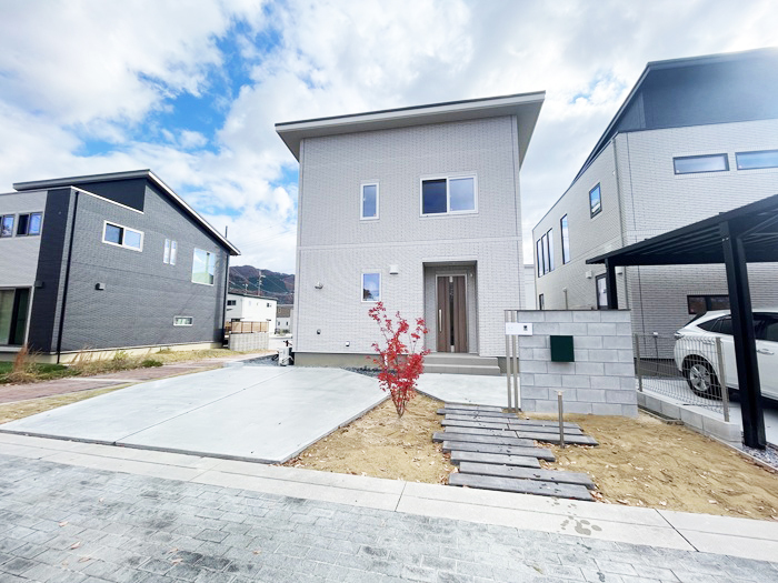 大阪府箕面の新興住宅地ゆったりした敷地の余白をいかしたシンプルなデザイン外構です。変形のガレージ土間と飛び石のようなアプローチがおしゃれです。土の部分にはお客様が砂利を入れられるそうです 一般的なコンクリートブロックを丁寧に馬目地で積むことでモダンな印象を