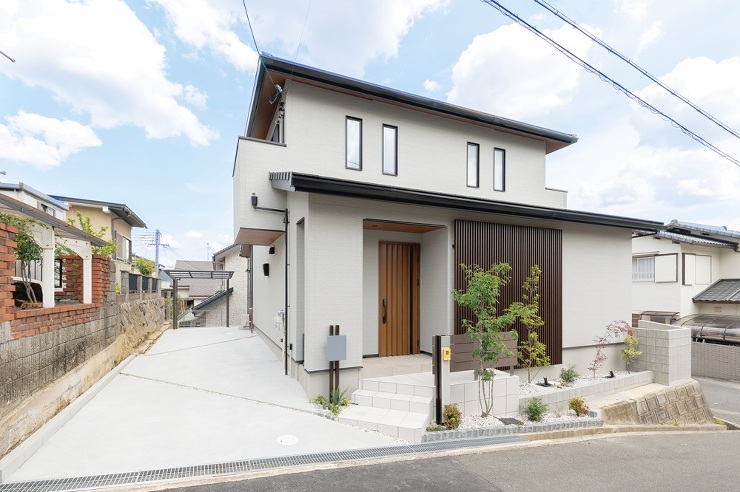 道路から立ち上がった擁壁がわに住宅が建ち隣地の住宅から離れているのでそちらを奥に長いガレージにしモルたり土間としています。その奥に自転車用のサイクルポートが見えます