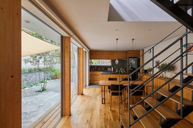 庭に面した連続する窓が広がるダイニング・キッチンの写真。窓からの光が室内の素材感を引き立て、開放的で落ち着いた空間を生み出しています。