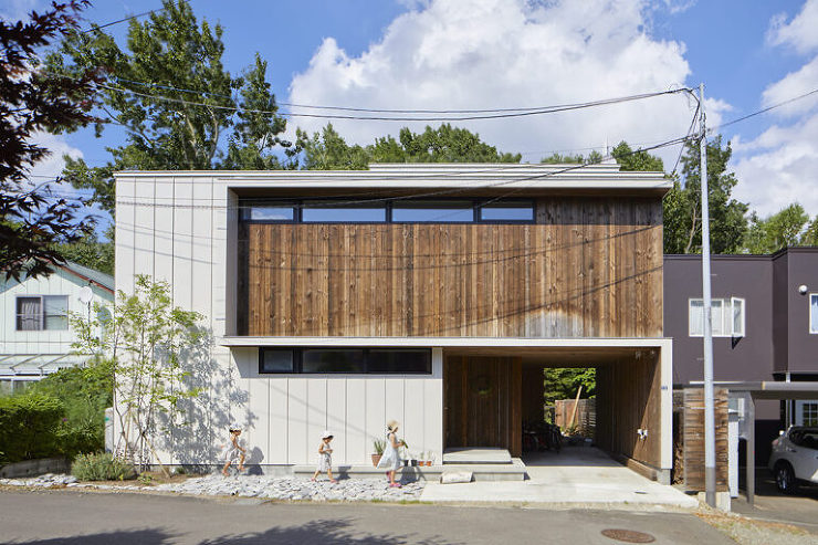 La Forêt住宅の外観、南側に建物が寄せられ、北側に広がる庭。庭へ通じるカーポートはトンネル状で、森の環境に合わせた板貼りデザイン。