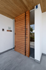 【玄関ポーチ】ダイナミックに伸びる木貼り天井の庇に誘い込まれるような導線を感じる玄関